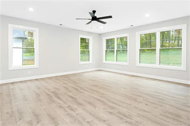 a view of an empty room with a window and wooden floor