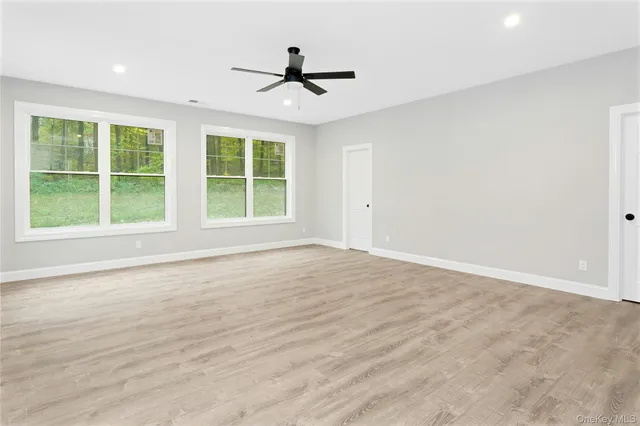 a view of an empty room with a window and wooden floor