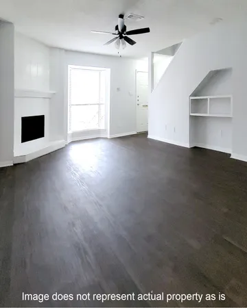 a view of empty room with wooden floor and ceiling fan