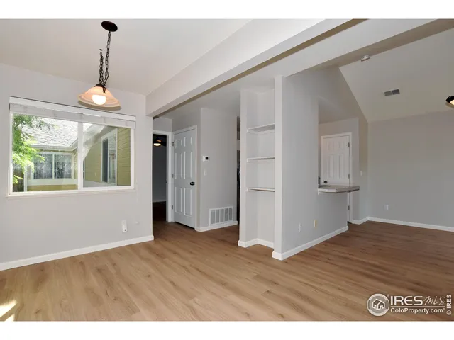 a view of an empty room with wooden floor and windows