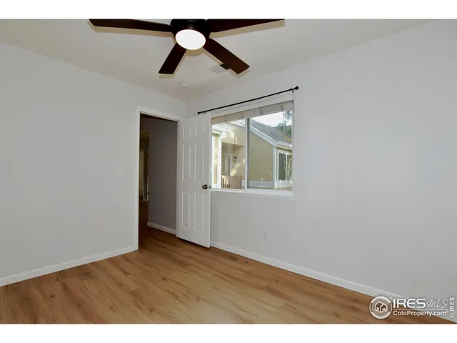 en empty room with wooden floor ceiling fan and window