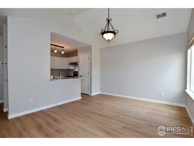 a view of kitchen and empty room with wooden floor