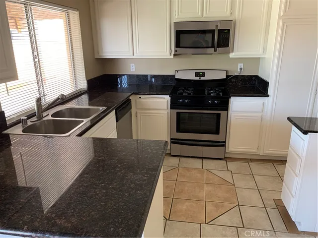 a kitchen with granite countertop a stove a sink and a microwave