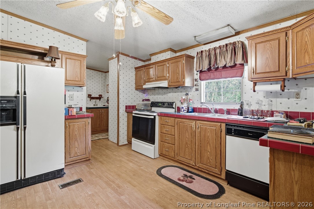 7307 Roslin Farm Road Hope Mills, NC 28348 - Photo 22 of 46 a kitchen with stainless steel appliances granite countertop a stove a sink dishwasher and a refrigerator with wooden cabinets