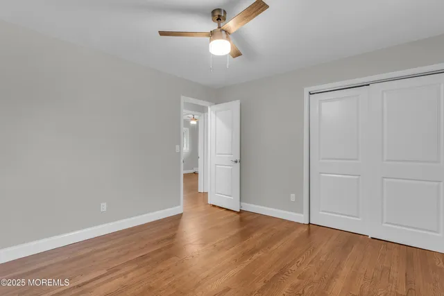 an empty room with wooden floor ceiling fan and window
