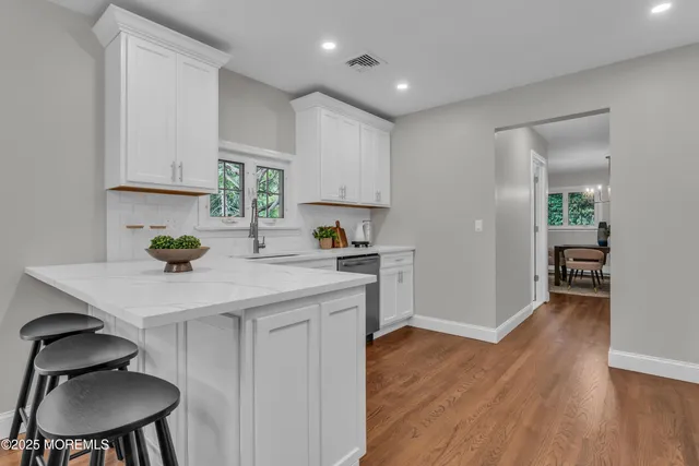 a kitchen with granite countertop a sink cabinets and wooden floor