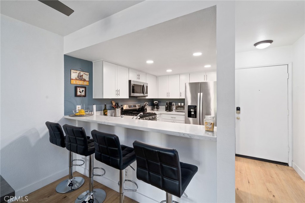 1237 East 6th Street, Unit 201 Long Beach, CA 90802 - Photo 3 of 27 a kitchen with a dining table chairs refrigerator and cabinets