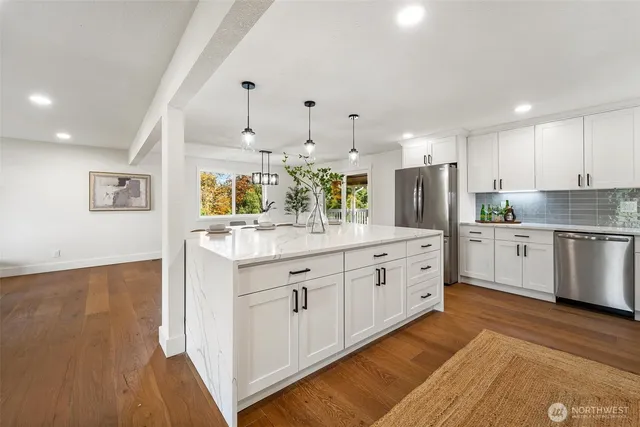 a large kitchen with stainless steel appliances granite countertop a stove top oven a sink and dishwasher