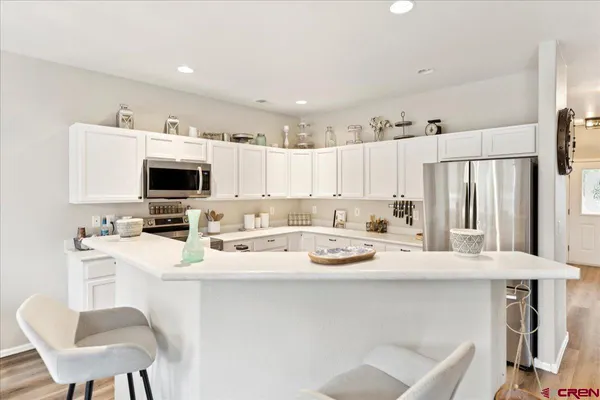 a kitchen with stainless steel appliances kitchen island granite countertop a sink a stove a microwave a refrigerator and white cabinets