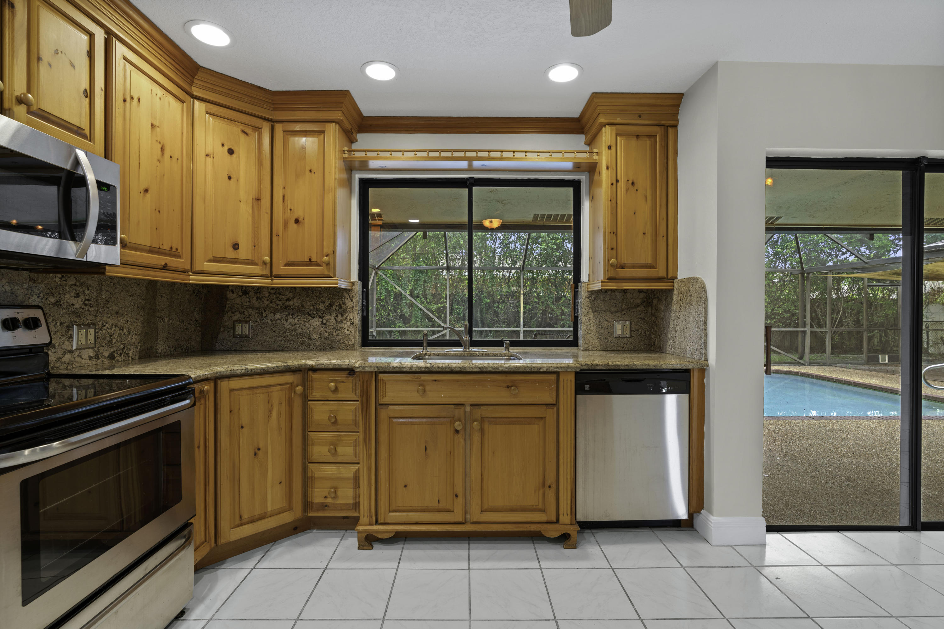 3375 Northwest 27th Avenue Boca Raton, FL 33434 - Photo 5 of 27 a kitchen with stainless steel appliances granite countertop a stove a sink and a microwave