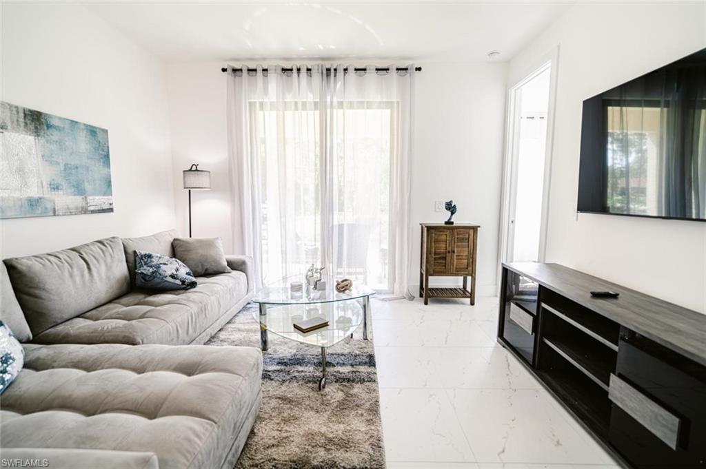 907 Homestead Road South Lehigh Acres, FL 33974 - Photo 15 of 43 Bright living area featuring large format white tile flooring, a glass sliding door with sheer curtains, recessed lighting, and a wall-mounted television