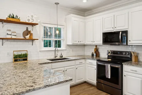 a kitchen with kitchen island granite countertop a sink a stove and cabinets