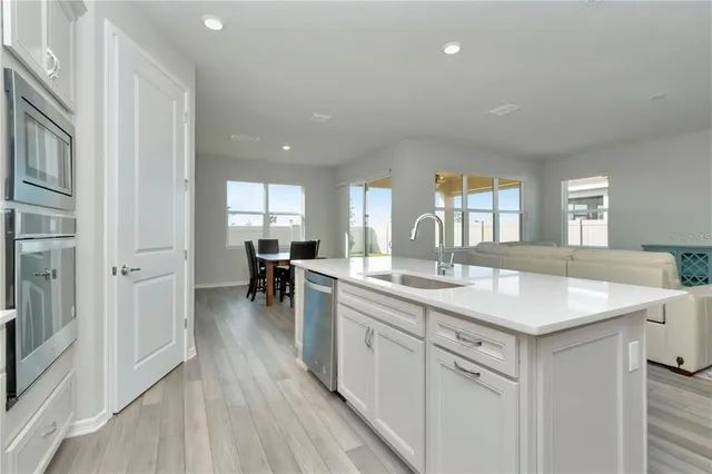 a kitchen with a sink dishwasher a stove and white cabinets with wooden floor