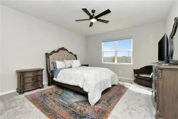 a bedroom with a bed couch and windows