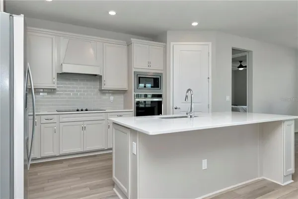 a kitchen with kitchen island white cabinets and refrigerator