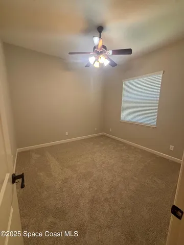 an empty room with a ceiling fan and a window