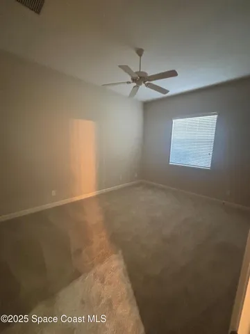 an empty room with a window and a fan