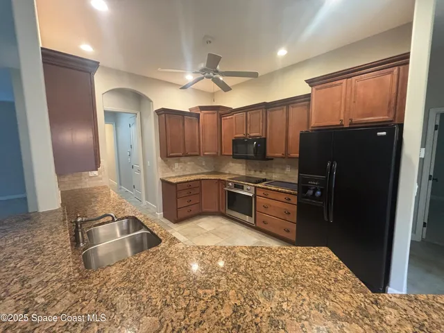 a kitchen with granite countertop a refrigerator stove top oven and sink