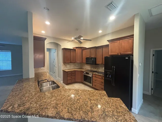 a kitchen with stainless steel appliances kitchen island granite countertop a refrigerator stove and sink