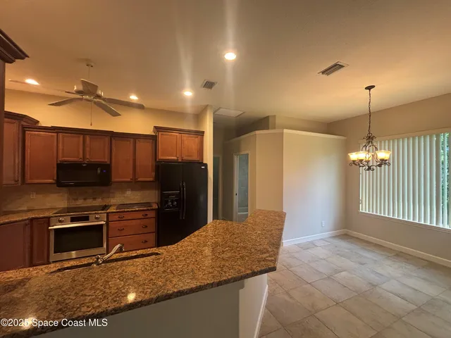 a kitchen with stainless steel appliances granite countertop a sink a stove and a refrigerator