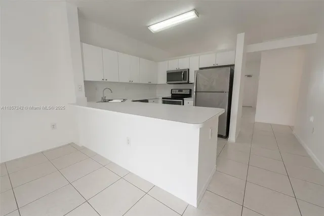 a kitchen with a sink a stove top oven and white cabinets