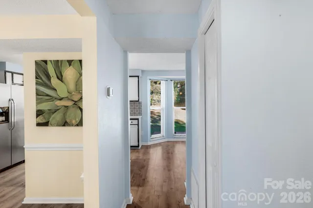 a view of a hallway with wooden floor and a living room