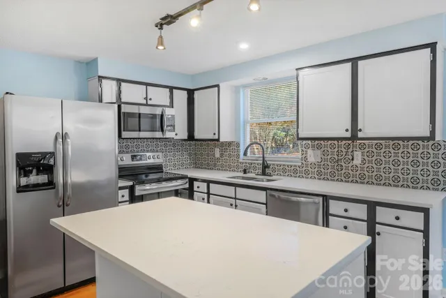a kitchen with stainless steel appliances a sink stove refrigerator and cabinets