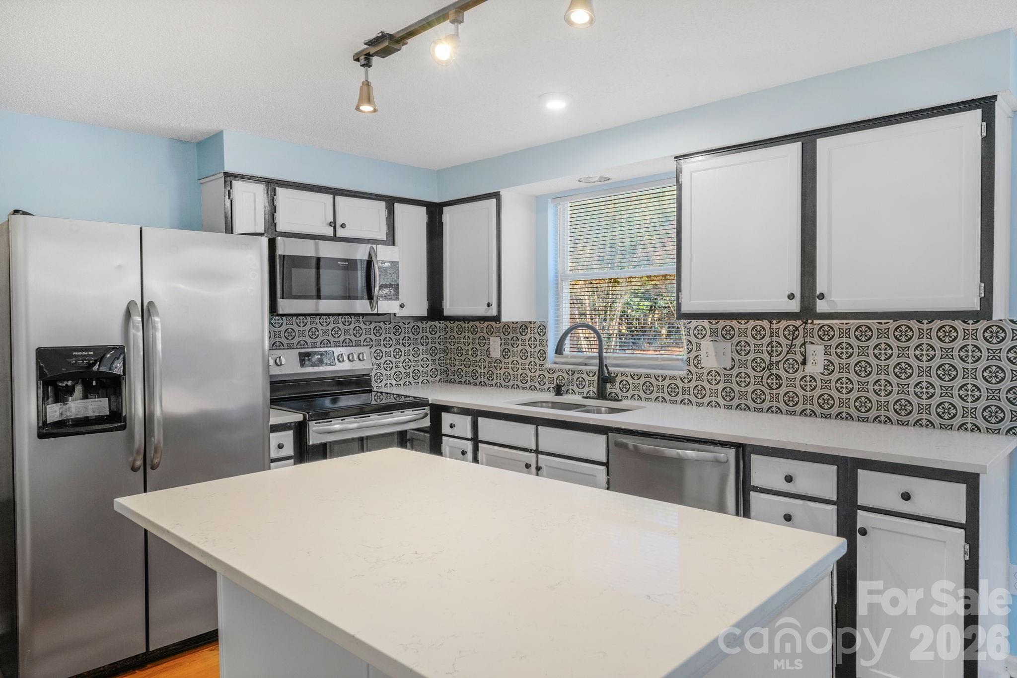 12006 Woodside Falls Road Pineville, NC 28134 - Photo 12 of 48 a kitchen with stainless steel appliances a sink stove refrigerator and cabinets