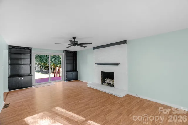 a view of an empty room with a fireplace and a window