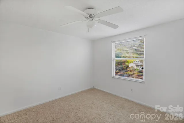 an empty room with a window and a ceiling fan