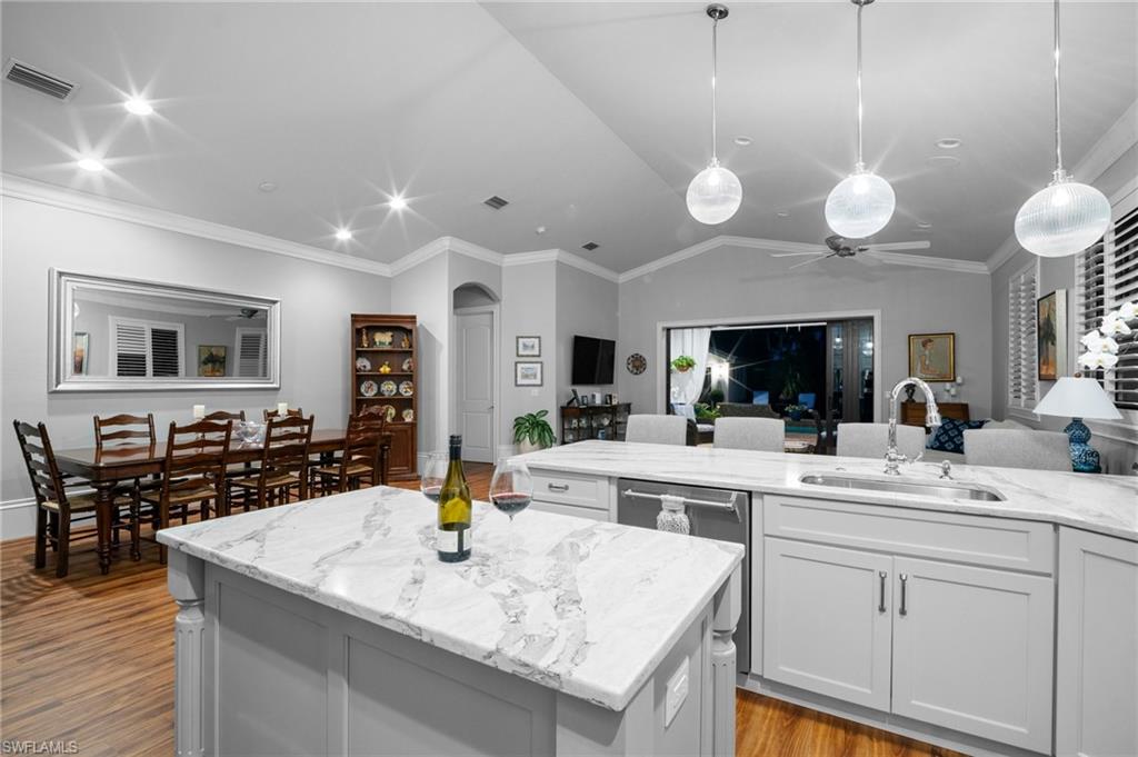 10340 Vanderbilt Drive Naples, FL 34108 - Photo 24 of 45 a large white kitchen with a large island oven a stove a dining table and chairs