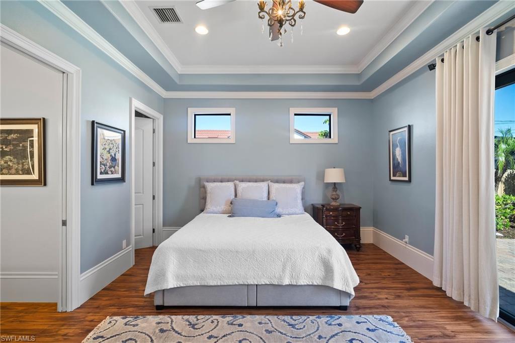 10340 Vanderbilt Drive Naples, FL 34108 - Photo 27 of 45 a bedroom with a bed and wooden floor