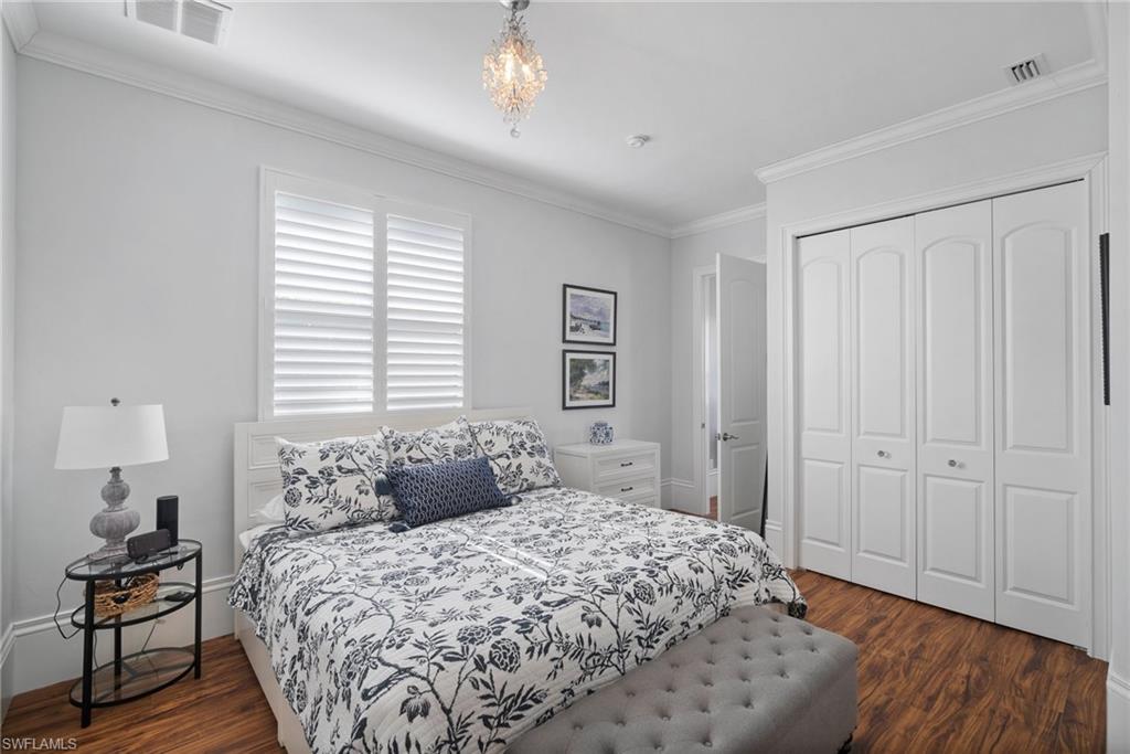 10340 Vanderbilt Drive Naples, FL 34108 - Photo 32 of 45 a bedroom with a bed and wooden floor