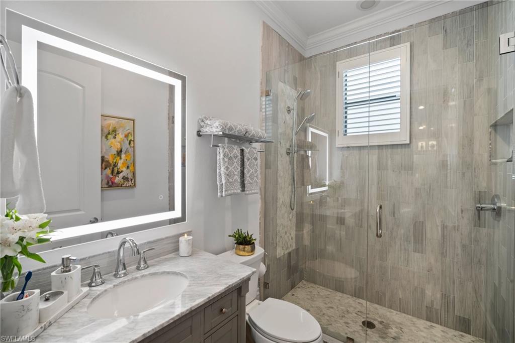 10340 Vanderbilt Drive Naples, FL 34108 - Photo 35 of 45 a bathroom with a granite countertop sink toilet a shower and a mirror