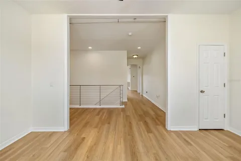 a view of empty room with wooden floor and fan