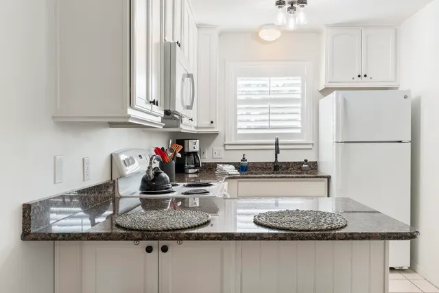 a kitchen with kitchen island granite countertop a sink a window and cabinets