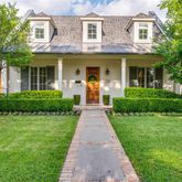 a view of a brick house with a yard potted plants and a table and chair