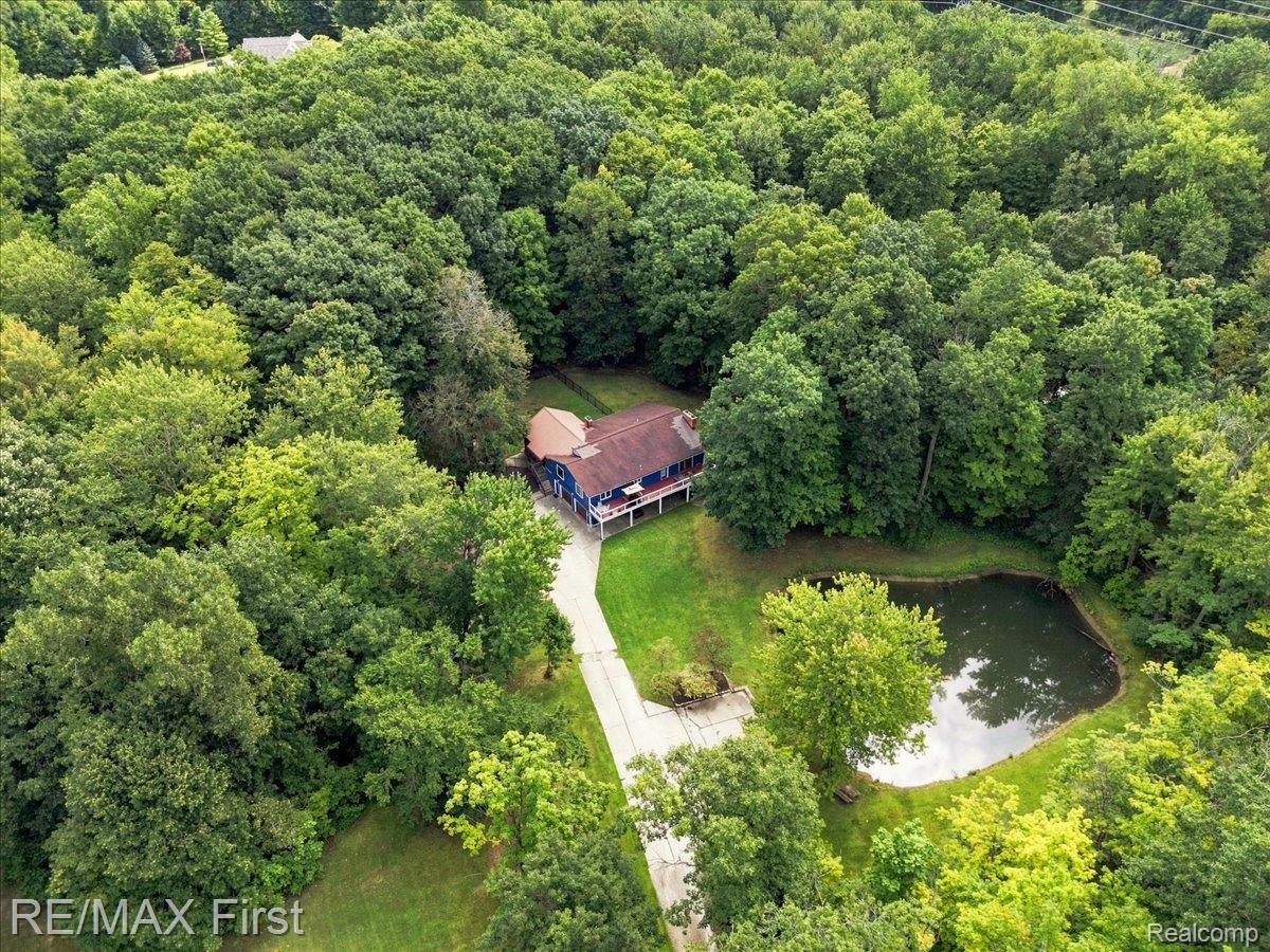 66200 Campground Road Washington, MI 48095 - Photo 6 of 62 Secluded property featuring a residence with a covered porch, a private pond, and a concrete driveway, surrounded by mature trees