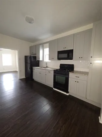 a kitchen with granite countertop a stove top oven a sink dishwasher and a refrigerator with wooden floor
