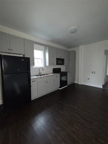 a view of empty room with wooden floor and electronic appliances