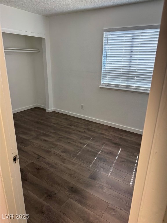 2377 Exeter Drive, Unit 3 Las Vegas, NV 89156 - Photo 5 of 13 Unfurnished bedroom with dark wood-style floors, a textured ceiling, and a closet