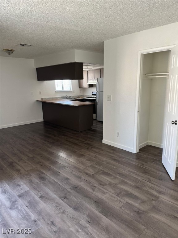 2377 Exeter Drive, Unit 3 Las Vegas, NV 89156 - Photo 13 of 13 Kitchen with a textured ceiling, a peninsula, dark wood-type flooring, open floor plan, and white appliances