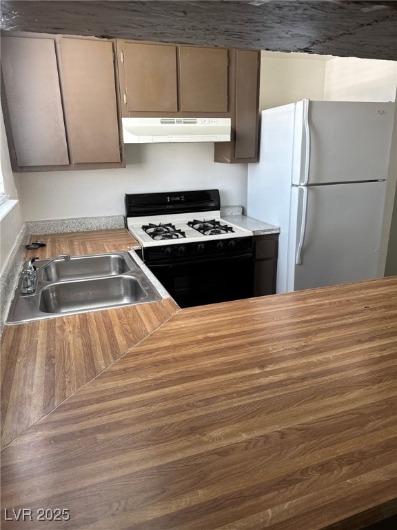 2377 Exeter Drive, Unit 3 Las Vegas, NV 89156 - Photo 8 of 13 Kitchen with gas stove, freestanding refrigerator, under cabinet range hood, and wooden counters
