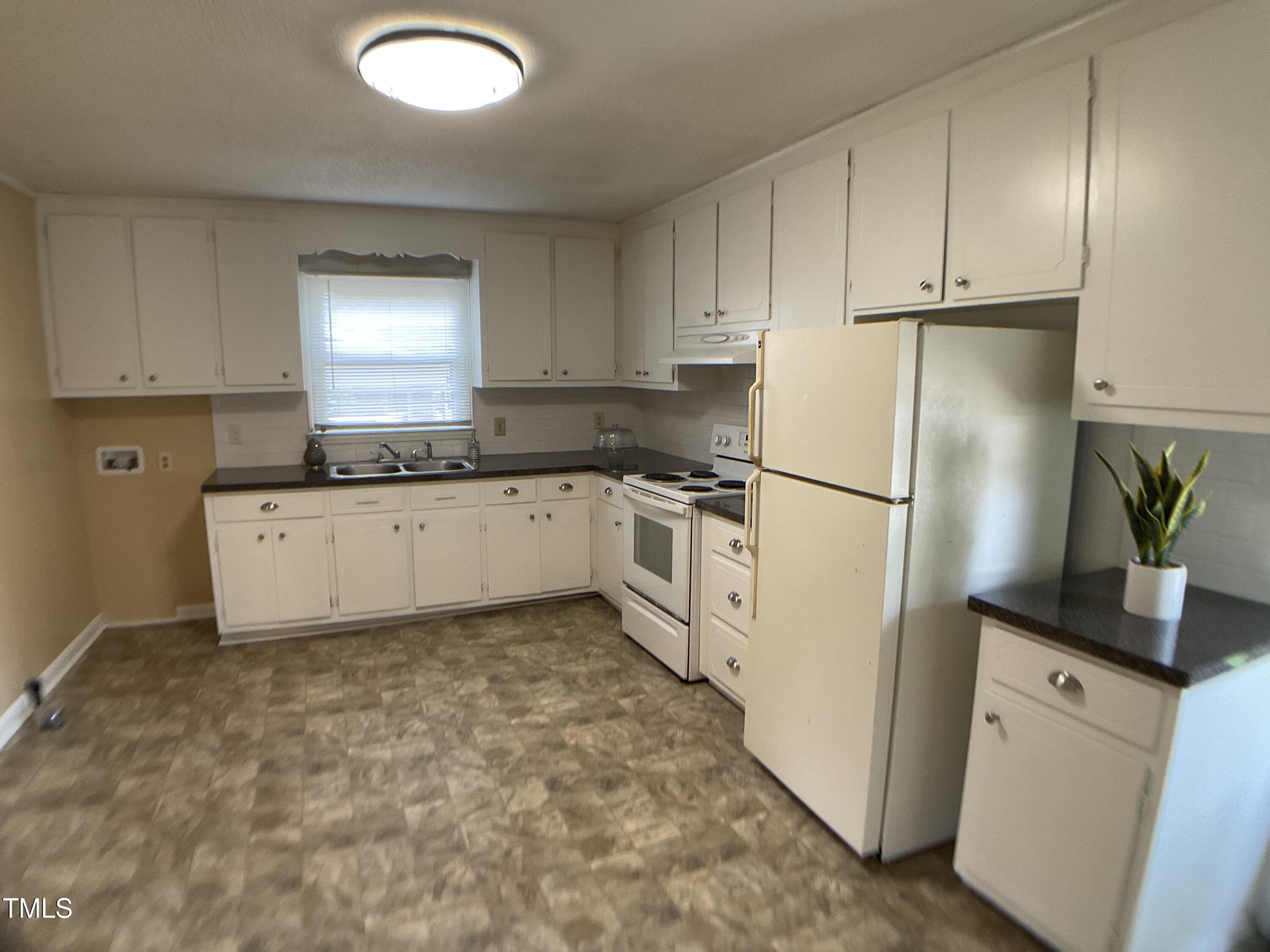 2915 Ross Road Durham, NC 27703 - Photo 5 of 21 a kitchen with granite countertop a refrigerator sink stove and white cabinets