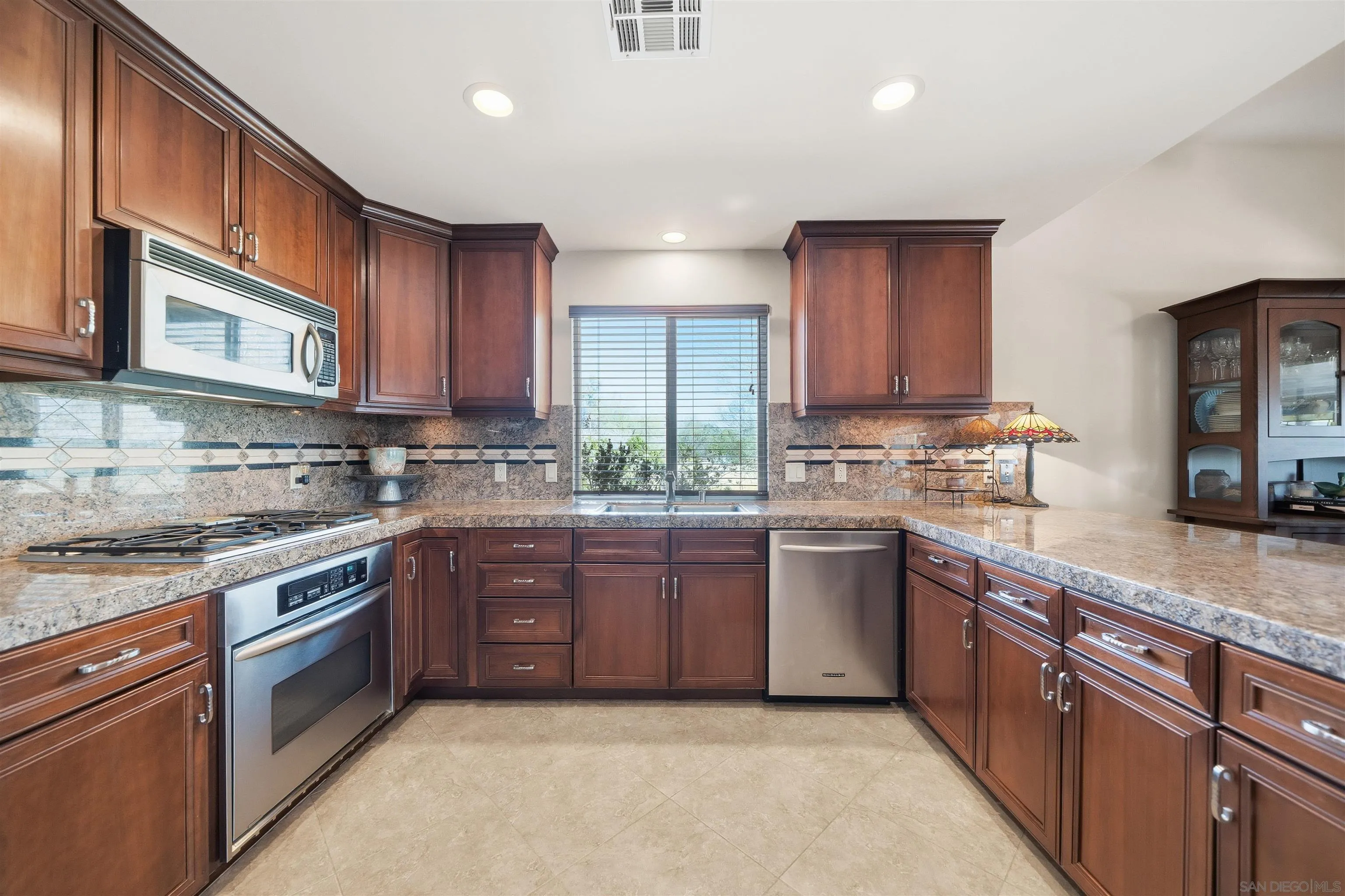 a kitchen with stainless steel appliances granite countertop wooden cabinets a stove top oven a sink and dishwasher