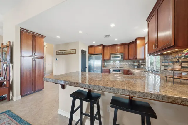 a kitchen with stainless steel appliances granite countertop a table chairs sink and cabinets