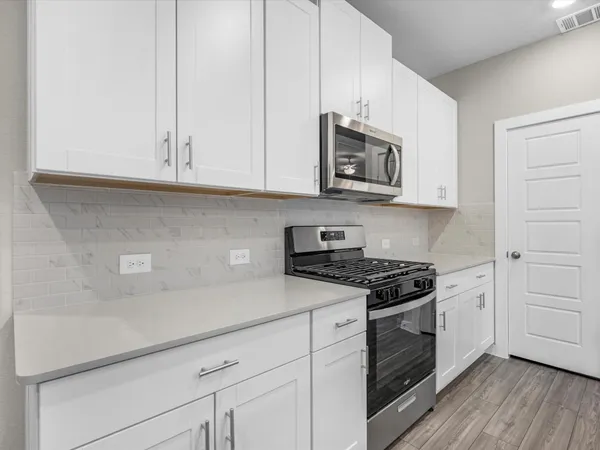 a kitchen with stainless steel appliances granite countertop white cabinets and a stove a oven with white countertops