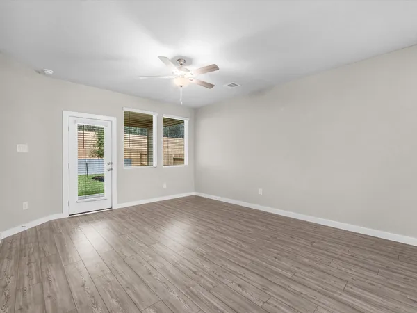 a view of an empty room with wooden floor and a window