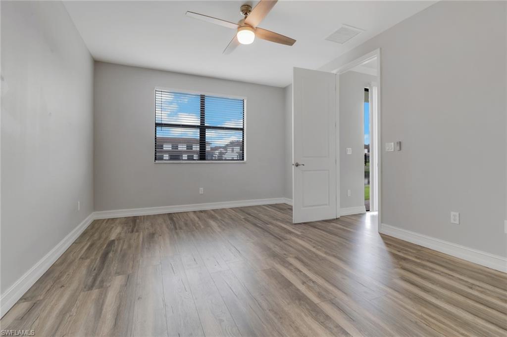 7948 Bristol Circle Naples, FL 34120 - Photo 14 of 27 an empty room with wooden floor and windows