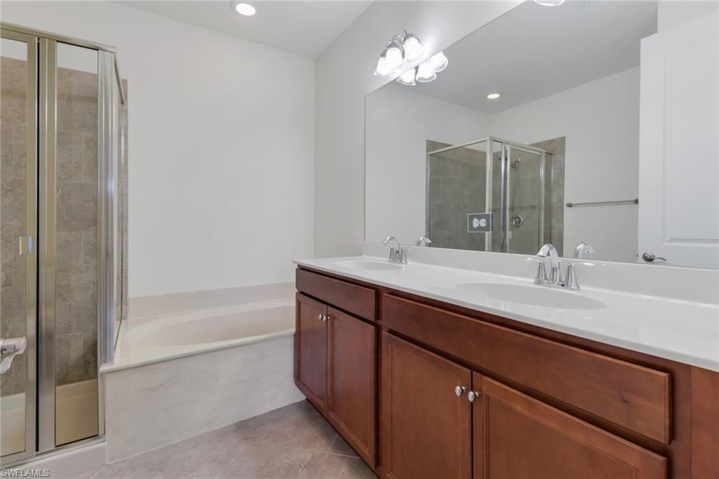 7948 Bristol Circle Naples, FL 34120 - Photo 15 of 27 a bathroom with a bathtub a sink and a mirror